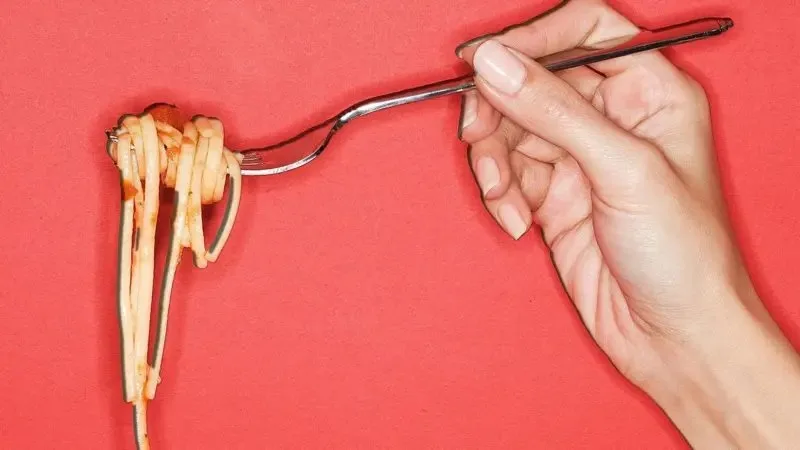 Spagetti dolamış bir çatalı tutan el.