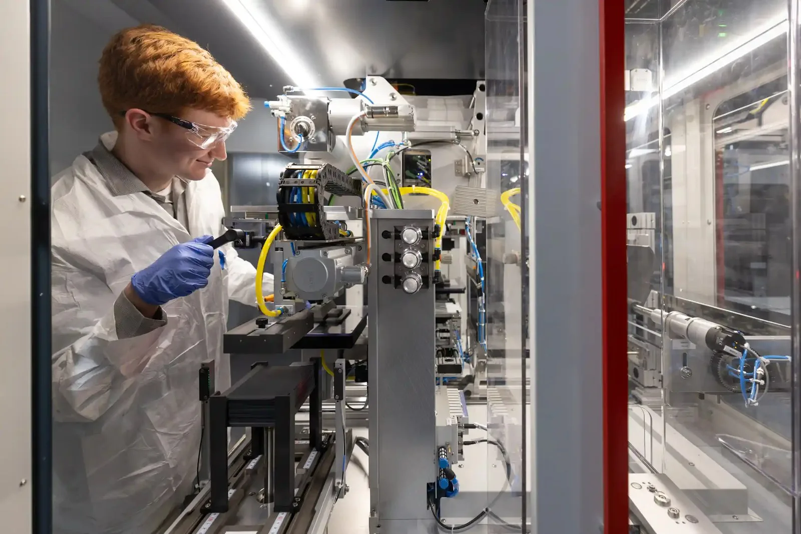 An intern in the clean energy program BATTERI calibrates an assembly stacker.