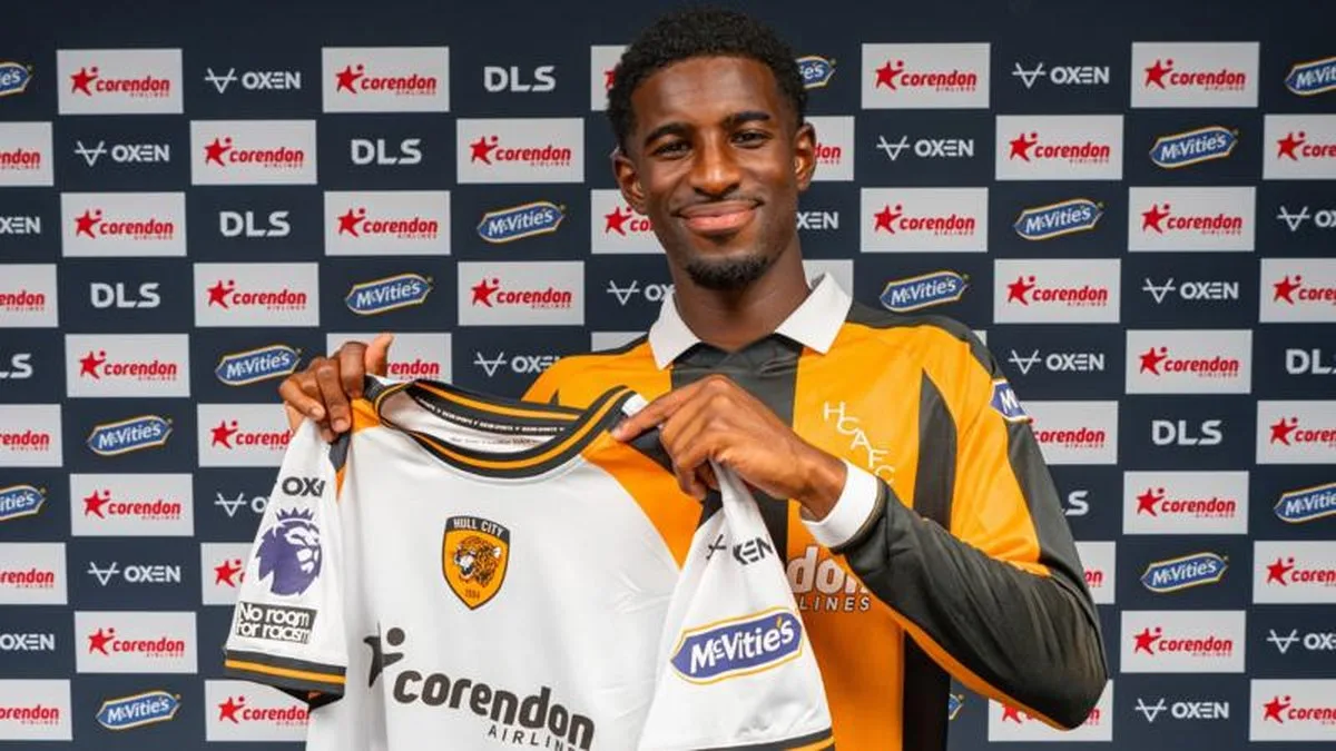 Hull City's new signing Mohamed-Ali Cho poses in the club's yellow and black home shirt, while holding up their white away strip