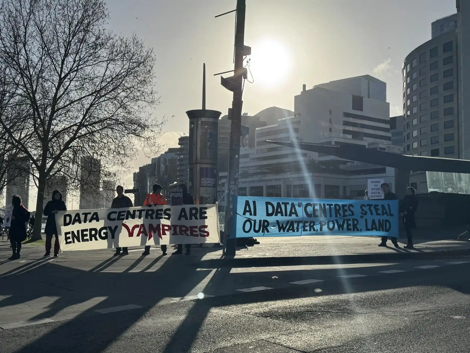 people protesting data centres, banners talking about environmental impact. cold day in city.