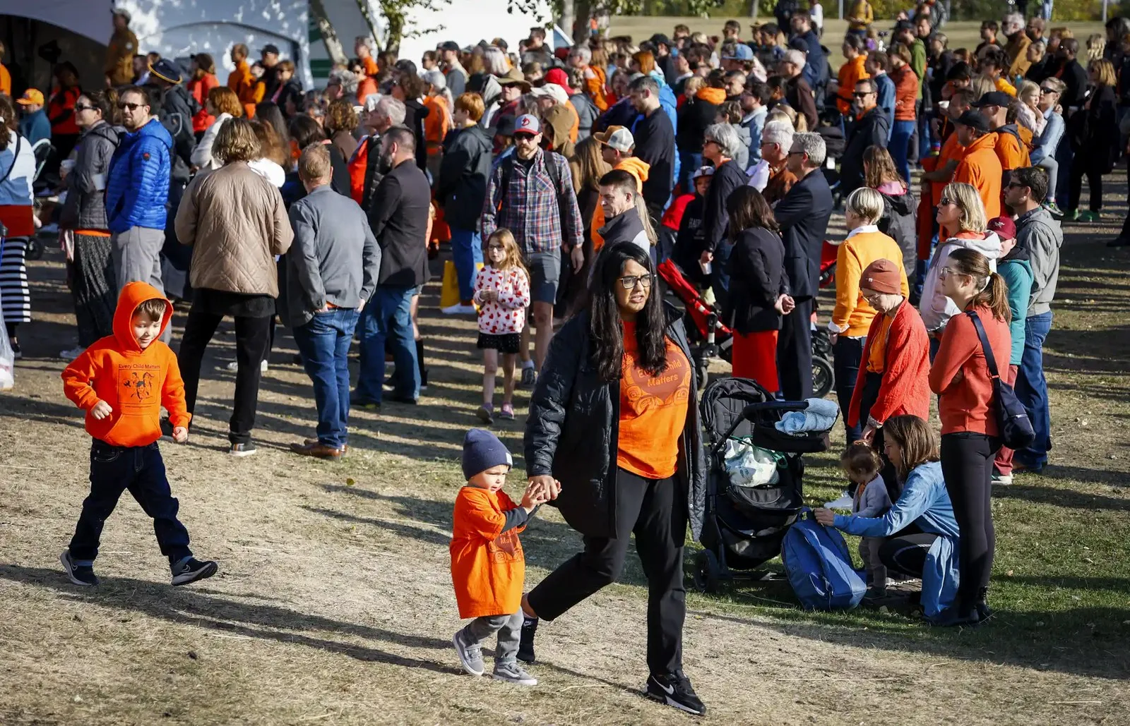 People seen walking in orange T-shirts outdoors.