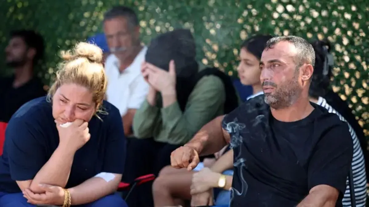 Bir sarışın kadın ve yanında siyah tişörtlü bir erkek var. İkisi de çok üzgün görünüyor. Arkalarıda başörtlülü bir kadın ellerini kafasına koymuş. Bunlar bekleme halindeki kurban yakınları