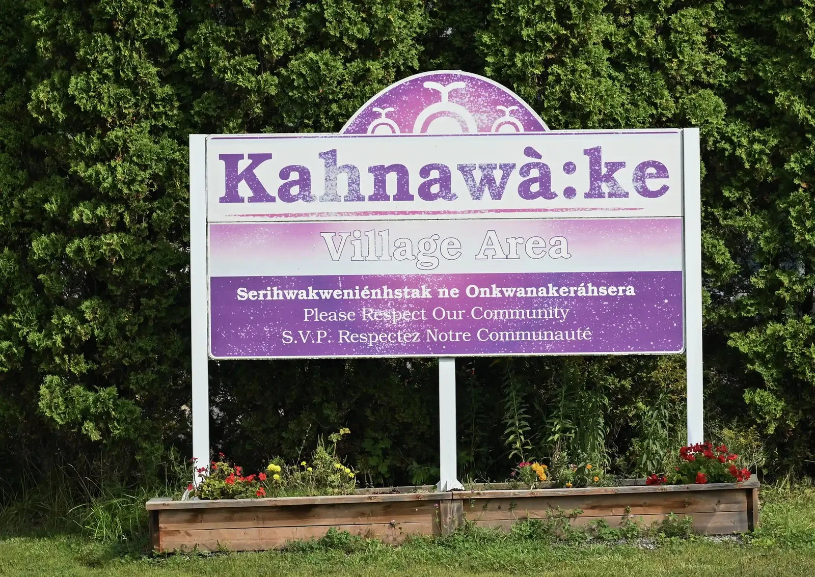 A purple sign says Kahnawà:ke - please respect our community.