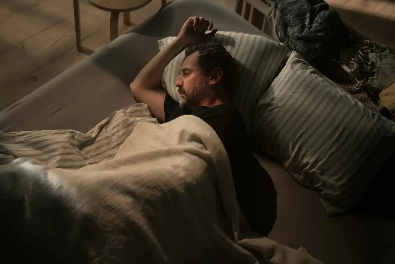 A man lies in bed in a dark room