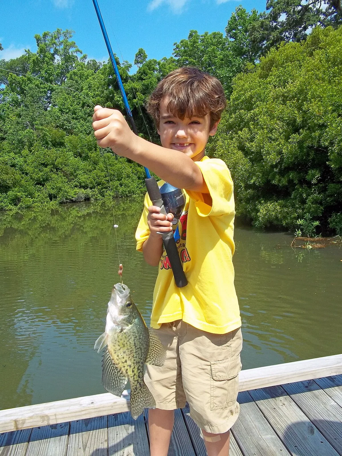 A young angler who has successfully hooked a black crappie in the mouth