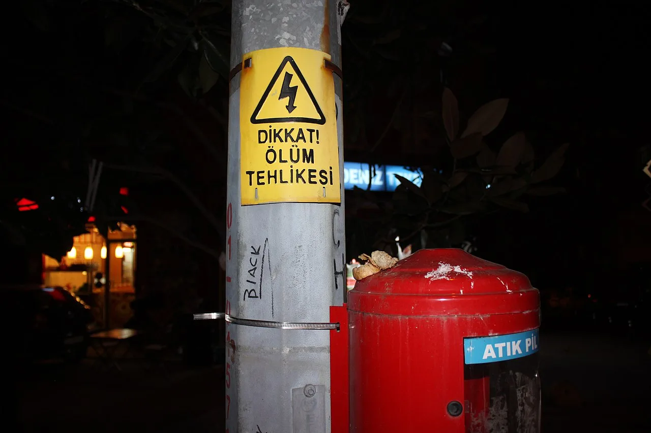 Bir elektrik direği üzerinde "Dikkat Ölüm Tehlikesi" uyarı levhası