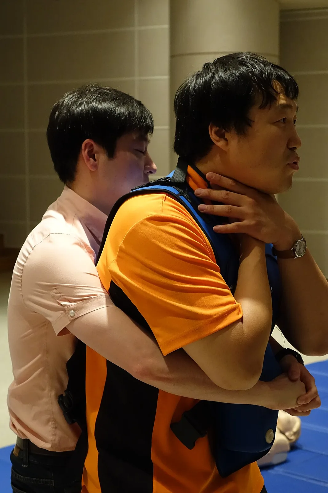 The man on the right is performing the universal sign of choking by placing both hands on his throat.