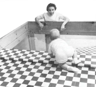 An example of a visual cliff experiment. A mother urges her child from across the deep side of the visual cliff. Despite a transparent surface covering the cliff, the child hesitates to move forward.